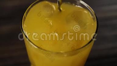 调酒师用<strong>勺子</strong>在<strong>一个</strong>高大的玻璃杯里用新鲜的橙汁搅拌冰块和木桌上的俯视图